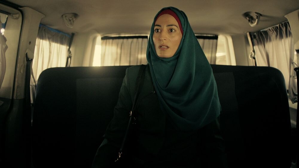 Laëtitia Eïdo v hidžábu sedící v autě s ustaraným výrazem v seriálu Fauda.
