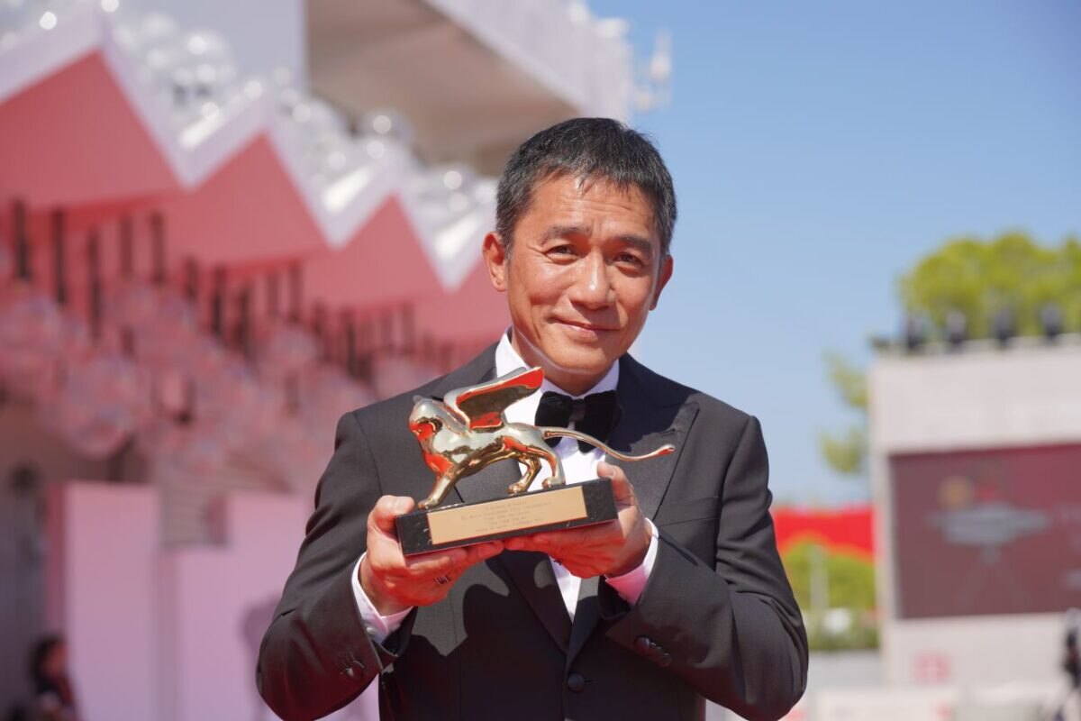 Tony Leung Chiu-Wai na filmovém festivalu v Benátkách získal cenu Zlatého lva, kterou drží v ruce.
